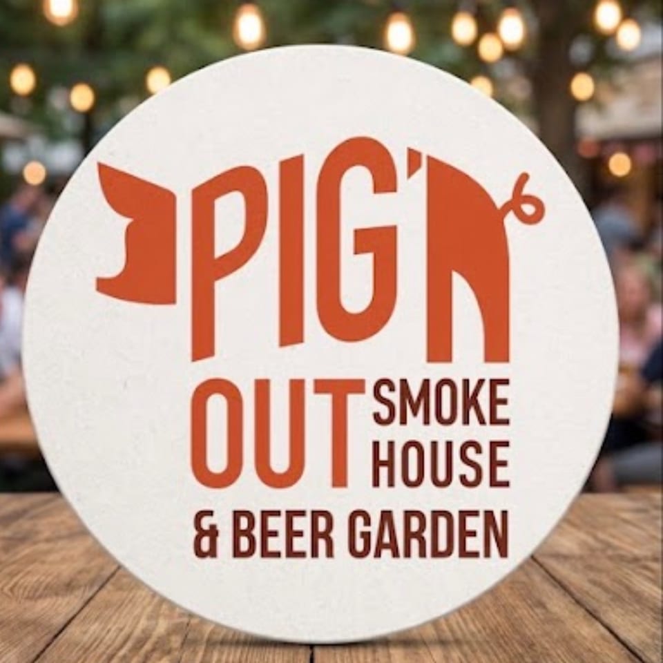 Pig Out Smoke House & Beer Garden logo displayed on a round sign against a warmly lit restaurant background.